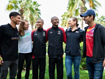 six people hurdled up with arms around each other and looking and smiling